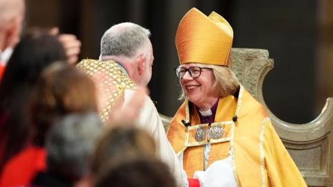 Mullally holds the hand of the Very Revd Dr David Monteith as she's installed as the new archbishop, with other clergymembers in the foreground, in Canterbury cathedral on Wednesday.