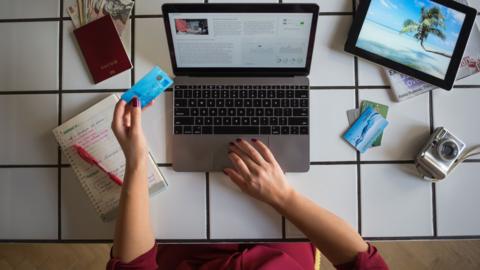 Young woman using laptop, paying with credit card, travel booking