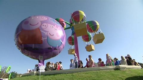 A balloon with peppa pig on in front of a hot air balloon themes ride