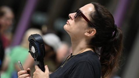 A woman in black with a hand-held fan