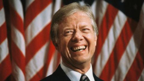 Jimmy Carter standing in front of the US flag