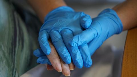 Older person's hand being held by a carer