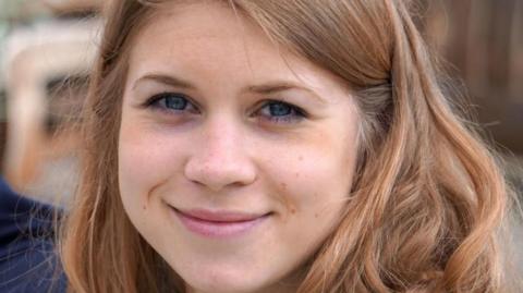 Sarah Everard, a young woman, with shoulder length borwn hair, smiles for the camera