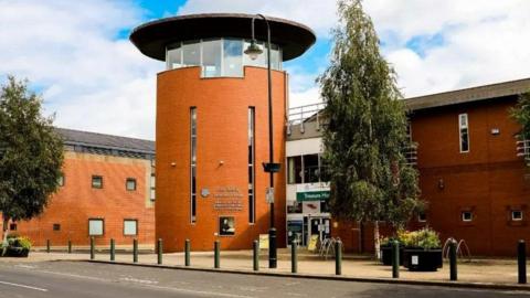 The exterior of the Champney Treasure House, which houses Beverley Art Gallery. The bricks are a terracotta colour and the front of the building is a cylindrical shape with a row of windows around the top and a flat, dark roof. 