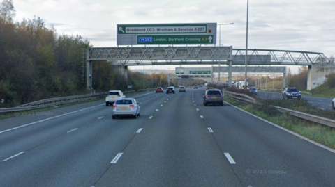 A Google Street image of the London-bound carriageway of the A2 approaching Gravesend. The road has a hand-full of silver and dark-coloured cars on it and the green sign for London, the Dartford Crossing and Gravesend is overhead.