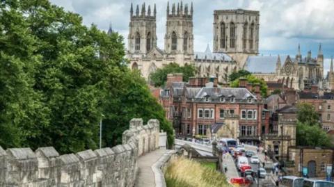 This is a classic shot of York Minster from the city's walls. It was taken from the stretch of the walls near to the railway station. Lendal Bridge across the River Ouse is busy with traffic in both directions.