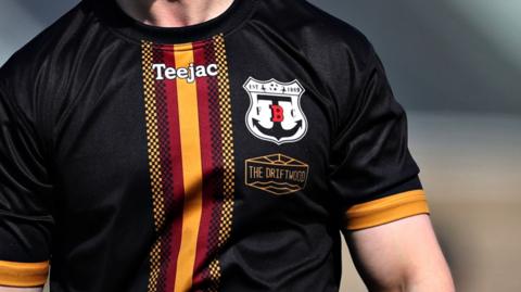 Man wearing black football shirt with Trearddur Bay logo