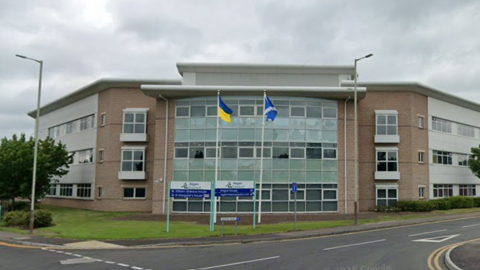 Angus Council's headquarters in Forfar, a two-storey building with a glass front and flags flying in front