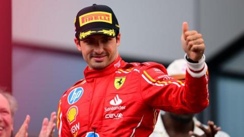 Ferrari driver Carlos Sainz gives a thumbs-up after a race