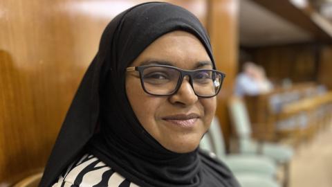 Councillor Repi Begum sat in Swindon Borough Council chamber wearing thick black rimmed glasses and a hijab