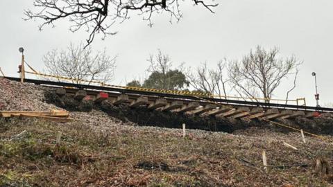 A picture from beneath the landslip, which shows train tracks dangling in the air.