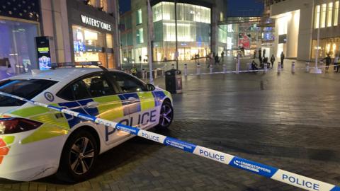 Police tape on the approach to the Bullring shopping centre. Waterstones is visible to the left, and a police car is in the foreground inside the cordon. 