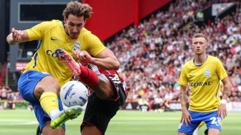 Birmingham City's Phil Neumann (centre, yellow shirt) is challenged by Sheffield United's Sam McCallum at Bramall Lane
