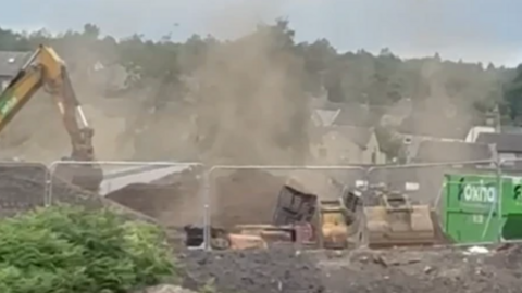 A building site with dust rising in the air 