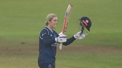 Georgia Adams raises her bat to acknowledge her century for Hampshire