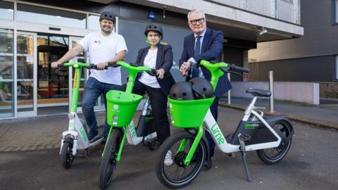 Tom Newham, Lime senior manager of public affairs, with Beccy Marston, West Midlands Active Travel Commissioner and Mayor Richard Parker. Two men and a woman pose on green and white e-bikes and e-scooters