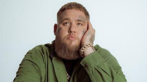 Rag'n'Bone Man dressed in a green shirt. He is looking away from the camera