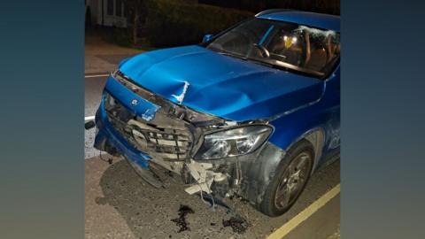 A blue Mercedes that has suffered significant damage to its entire front.