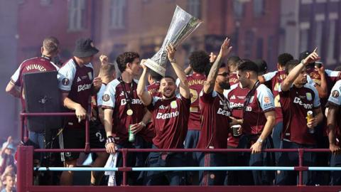 Emi Buendia of Aston Villa lifts the UEFA Europa League trophy on the team bus during the Aston Villa trophy parade