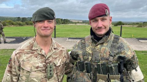 Two men standing in army uniform, looking at the camera wearing berets