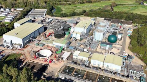 An aerial shot of Sandown Wastewater Treatment Works. It shows pipework and round and rectangular buildings on a densely-built site bordering fields.