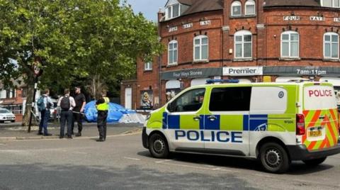 Four men standing near a police cordon on Reedswood Lane with a police van a short distance away