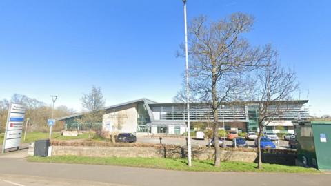 General view of Blaydon Leisure and Primary Care Centre. Several vehicles are in the car park at the front of the building.