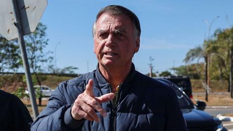 Brazil's former President Jair Bolsonaro gestures as he arrives to the State Secretariat of Penitentiary Administration headquarters in Brasilia, Brazil 