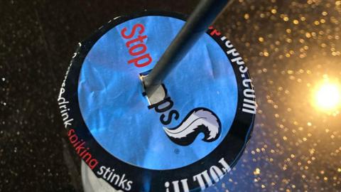 A drink with a cover on top of it to prevent spiking