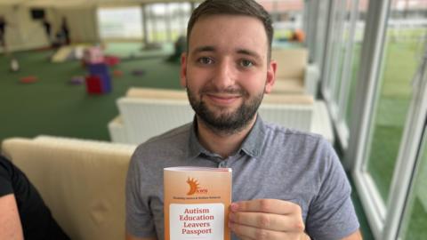 Luke Jackson holding up a copy of Dawn's autism education leavers passport