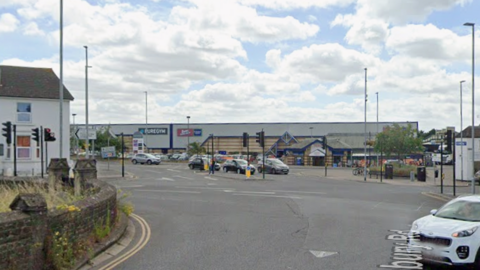 A Google Maps image of the junction with traffic lights, cars and people walking.