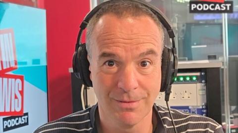 Martin Lewis wears heapphones and a striped shirt