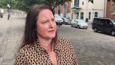 Alison Hernandez, the police and crime commissioner, looking off to the right and wearing a brown an black coloured button up shirt, she has long dark hair