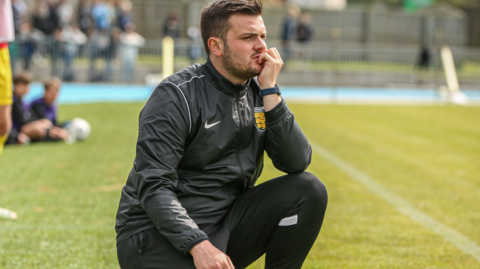 Elliot Powell crouched down on the sidelines