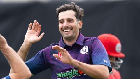 Charlie Cassell goes to high five a team-mate during his debut for Scotland