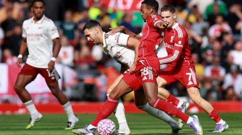A Liverpool player in all red on the right and an Arsenal 