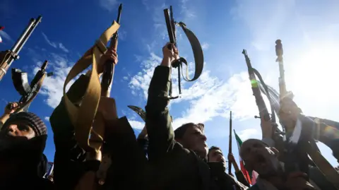 Houthi supporters shout slogans and raise their weapons during a rally in solidarity with Iran in Sana'a, Yemen, 27 March 2026.