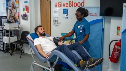 A nurse prepares a man for a blood donation on July 29, 2024 at the West End Donor Centre in London, England