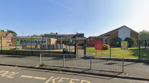 Single storey school buildings and a colourful playground behind a fence. A sign reads "St Paul's C of E Infant School".