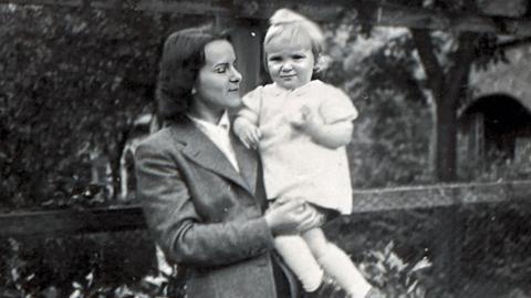 A black and white photo of a woman holding a young child. The woman is wearing late 1940s clothing.