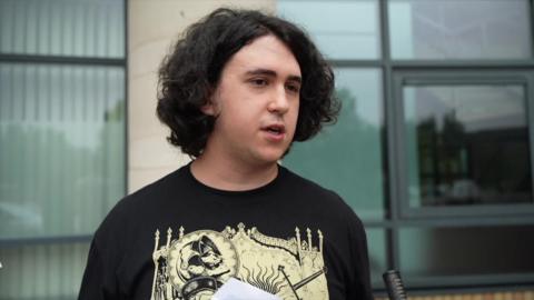 Student Aaron stands outside college holding results