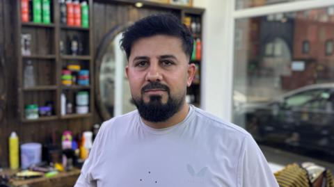 A man standing in a barber shop with a beard 