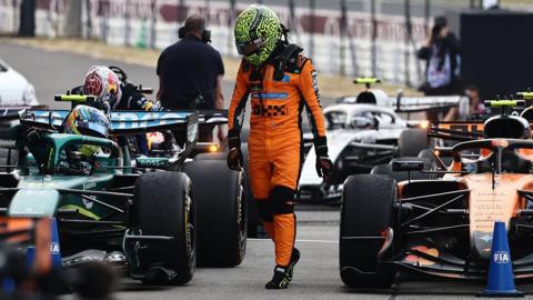 Lando Norris walks past a line of cars after the Japanese Grand Prix 