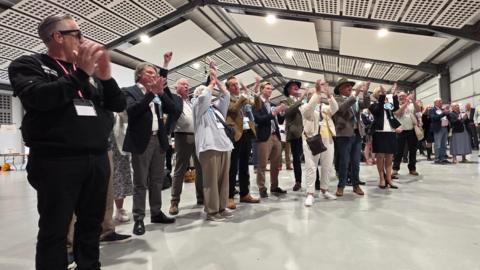 A line of people are standing and applauding