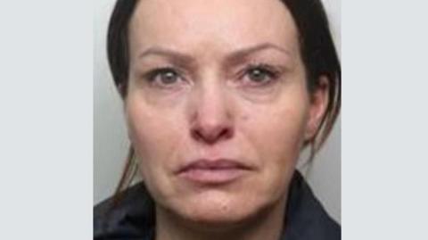 A picture of Lauren Millington's mugshot. She has brown hair tied back and appears to be crying or has been crying.