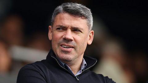 Jonathan Walters watches a game from the stands. He is wearing a navy blue jumper and a light blue shirt