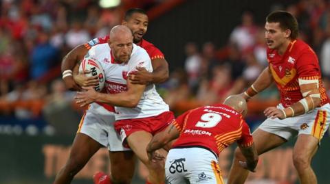 Dean Hadley carries the ball into a ruck of Catalan defenders