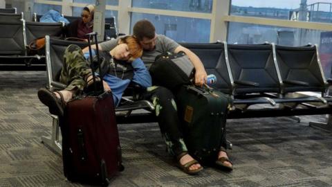 : Travelers rest where they can in the McNamara terminal at the Detroit Metropolitan Wayne County Airport on July 21, 2024 in Detroit, Michigan. 