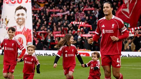 Virgil van Dijk of Liverpool enters the pitch with the children of former player Diogo Jota prior to the Premier League match between Liverpool and Wolves
