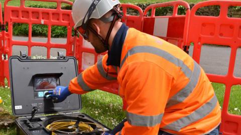 Engineer (name unknown) in orange hi-vis operates test equipment outdoors